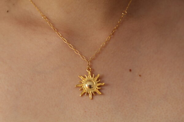 Cadena en forma de sol hecha en oro golfi expuesta en el cuello de una hermosa mujer