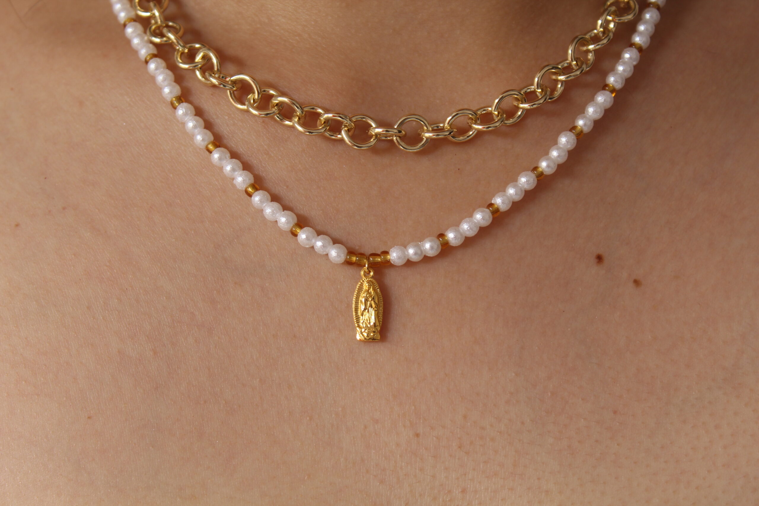 Cadena con dije de virgencita hecho en oro golfi expuesta por el cuello de una hermosa mujer