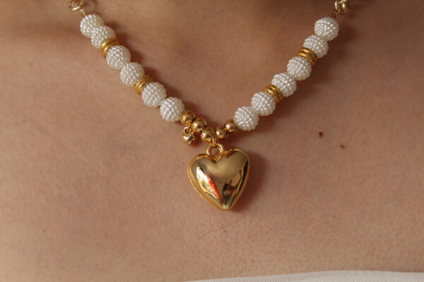 Cadena de perlas con un corazon hecho en oro golfi expuesto en el cuello de una hermosa mujer