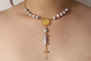 Camándula de rosas hecha en oro golfi expuesta en el cuello de una hermosa mujer