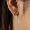 Aretes en forma de lagrima expuestos en la oreja de una hermosa mujer hechos en oro golfi