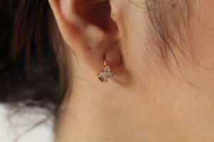 Aretes para mujer hechos en oro golfi con perlas brillantes expuestos en la oreja de una hermosa mujer