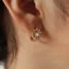 Aretes en forma de margarita los cuales están expuestos en una bella mujer y en material oro golfi