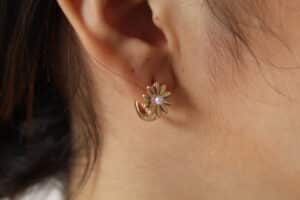 aretes_margarita_bonita Aretes en forma de margarita los cuales están expuestos en una bella mujer y en material oro golfi