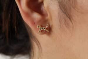 aretes_caballo Aretes en forma de caballo hechos en oro golfi expuestos en la oreja de una hermosa mujer