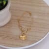 pulsera_conchita_de_mar Pulsera en forma de conchita hecha en oro golfi expuesta en una mesa con una flor de fondo