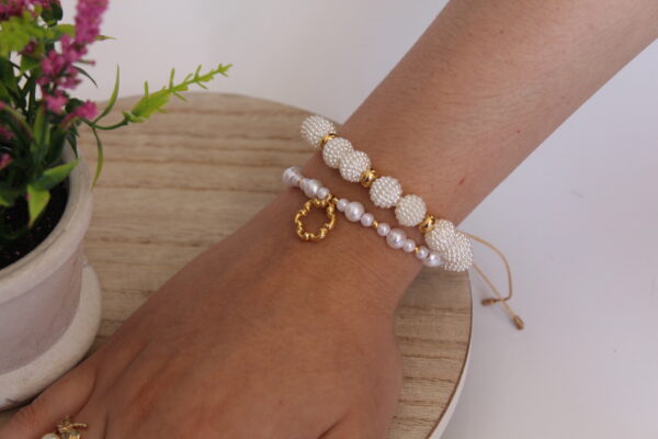 pulsera_perlas_brillantes Pulsera en forma de perlas echas en oro golfi expuestas en la mano de una hermosa mujer