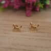 Aretes en forma de caballo hechos en oro golfi expuestos en una mesa con una flor de fondo