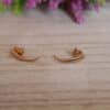 Aretes en forma de lagrima expuestos en una mesa con una flor de fondo