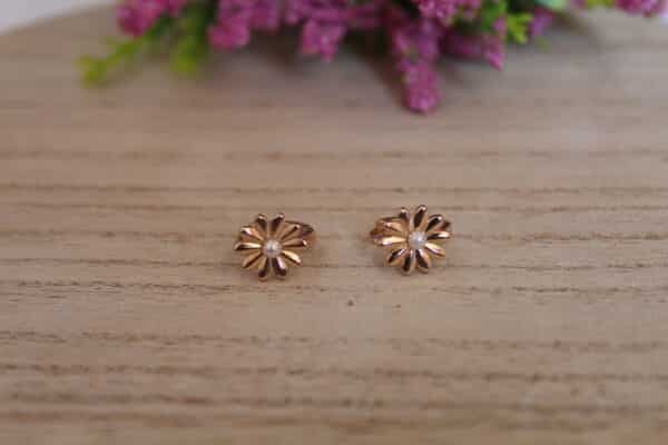 Aretes en forma de margarita los cuales están expuestos en una mesa y en material oro golfi