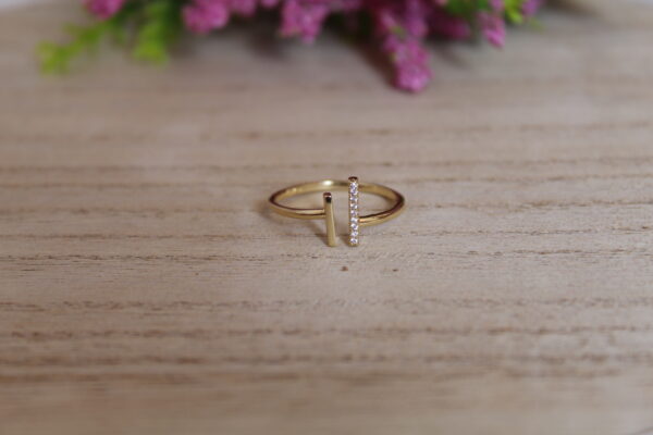 anillo_luxuryy Anillo en forma de luxury echo en oro golfi y tambien con perlas brillantes el cual esta puesto encima de una mesa con una flor de fondo